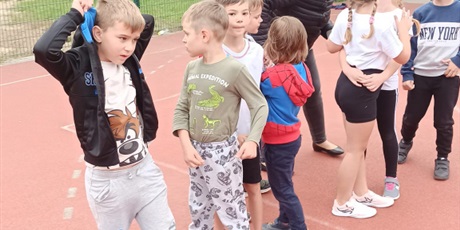 Powiększ grafikę: Grupa dzieci ubrana w stroje sportowe na boisku szkolnym.