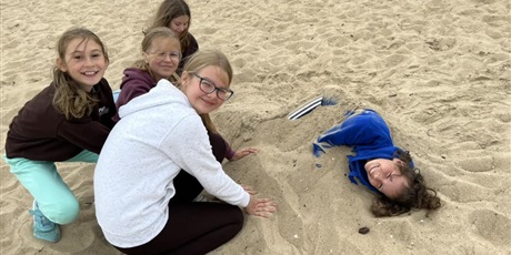 Powiększ grafikę: $ dziewczyny patrzące w obiektyw podczas zabawy w piasku na plaży.