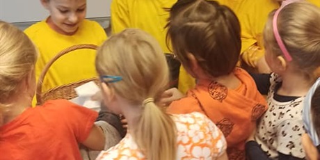Powiększ grafikę: Wolontariusze z klasy 3 ubrani w żółte koszulki sprzedają ciasteczka. Obok dzieci kupujące.