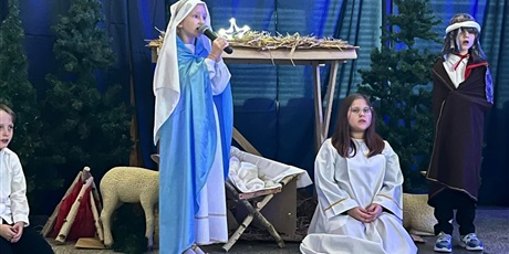 Powiększ grafikę: Dzieci przebrane w stroje Maryi i Józefa oraz aniołków przy stajence betlejemskiej. Maryja śpiewa kolędę: Lulajże Jezuniu