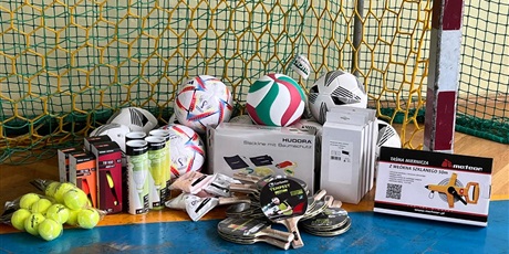 Powiększ grafikę: Widoczny sprzęt sportowy: piłki do tenisa, rakiety i piłki do tenisa stołowego, lotki do badmingtona, piłki do siatkówki.